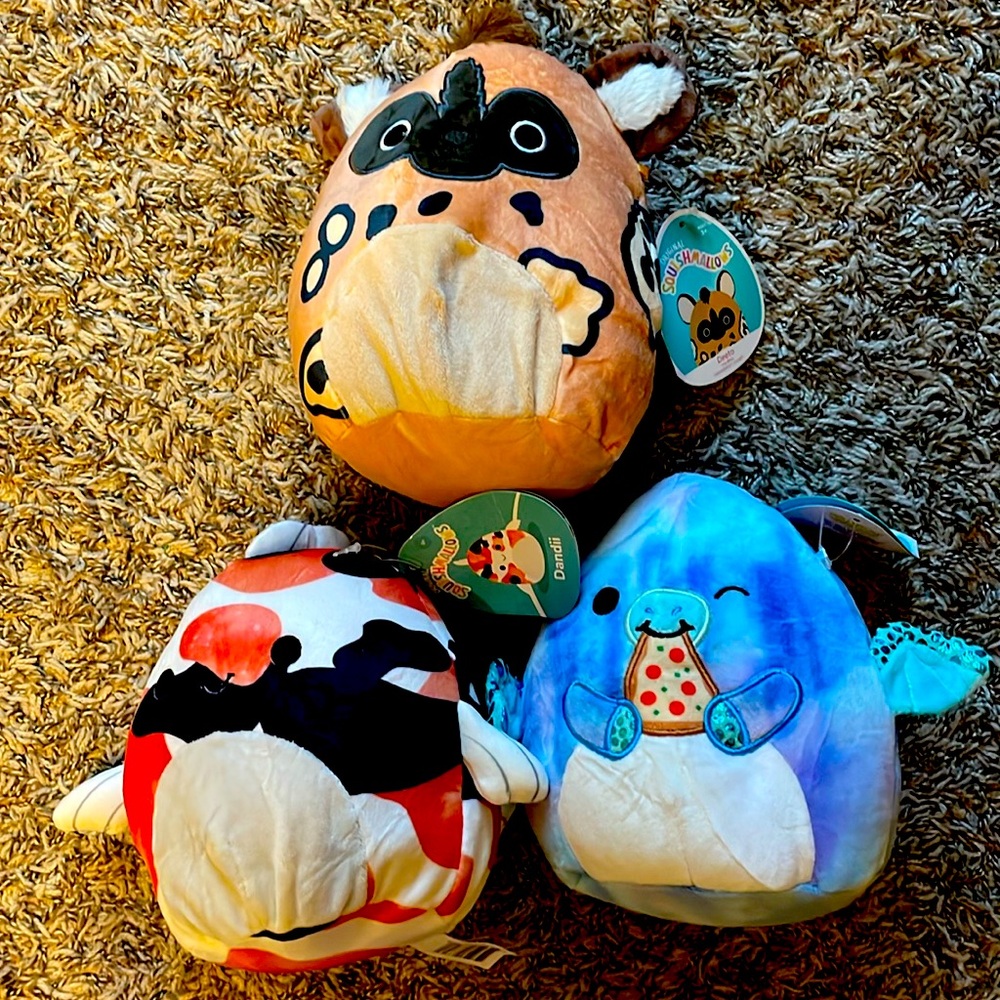 Three small squishmallows: koi fish, painted dog, pizza Dino.